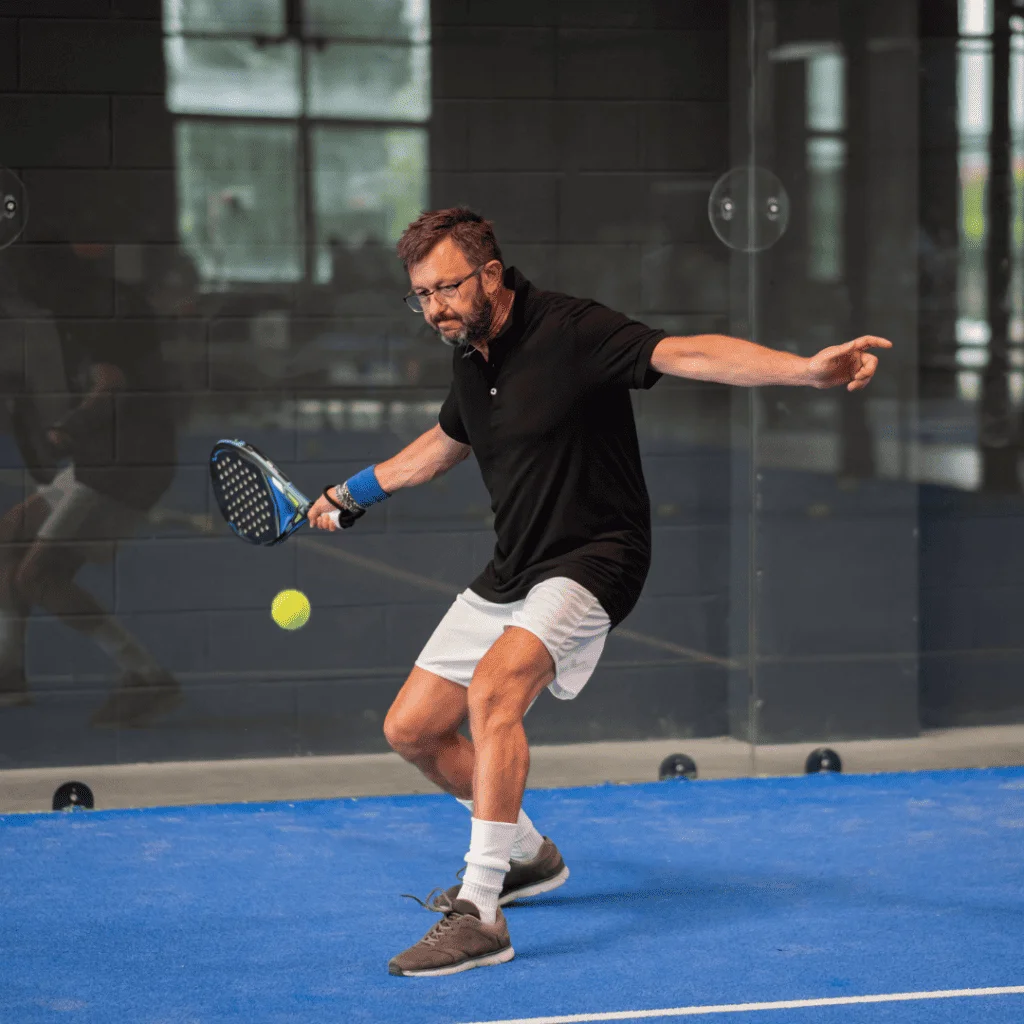 A man about to hit a padel shot on a padel court indoor