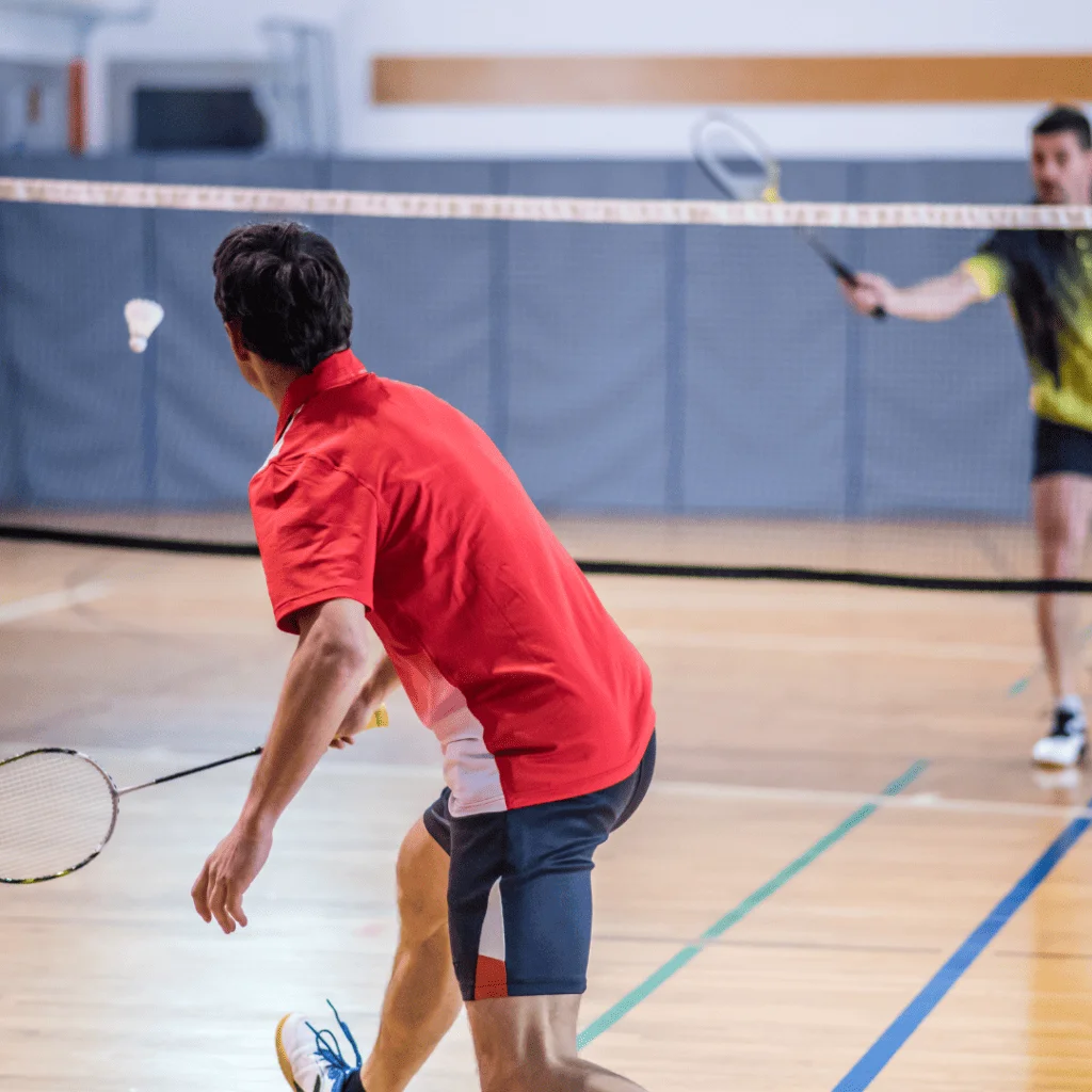 Two male players playing badminton indoor